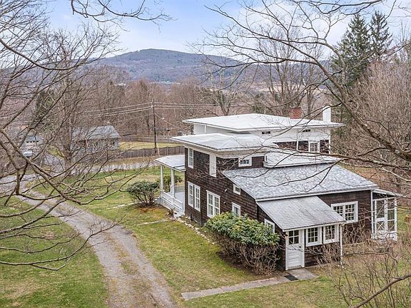 An aerial view of a house in the middle of a field with mountains in the background.