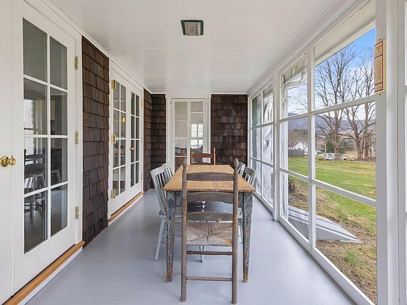 A screened in porch with a table and chairs