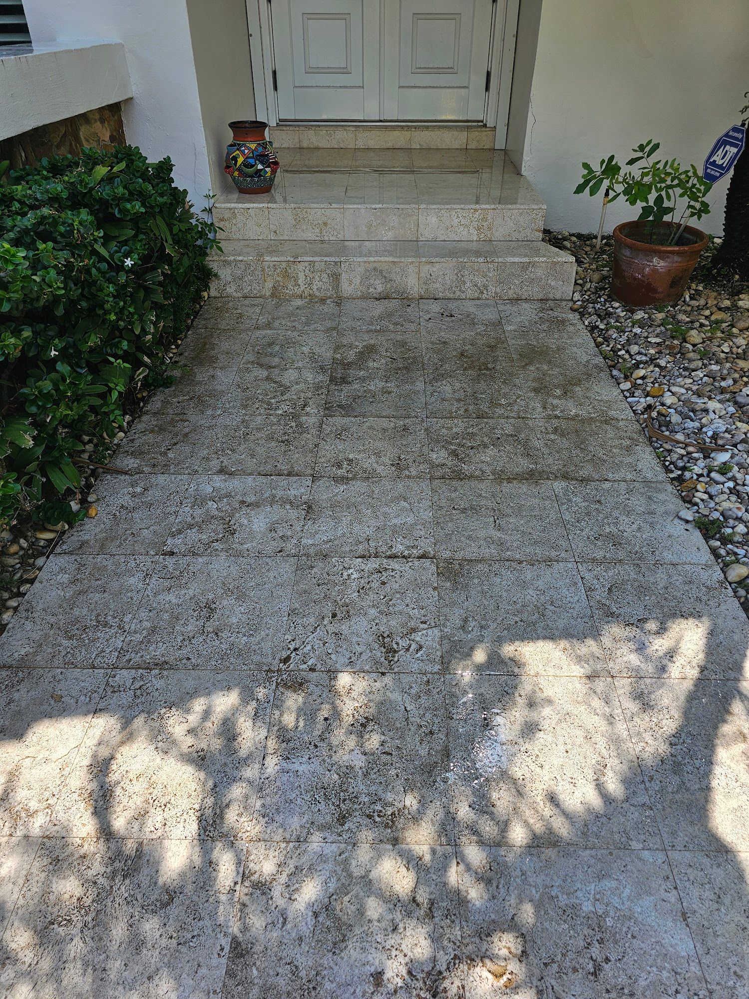 Concrete walkway and steps leading to a white double door entrance.  A decorative vase sits on top step.