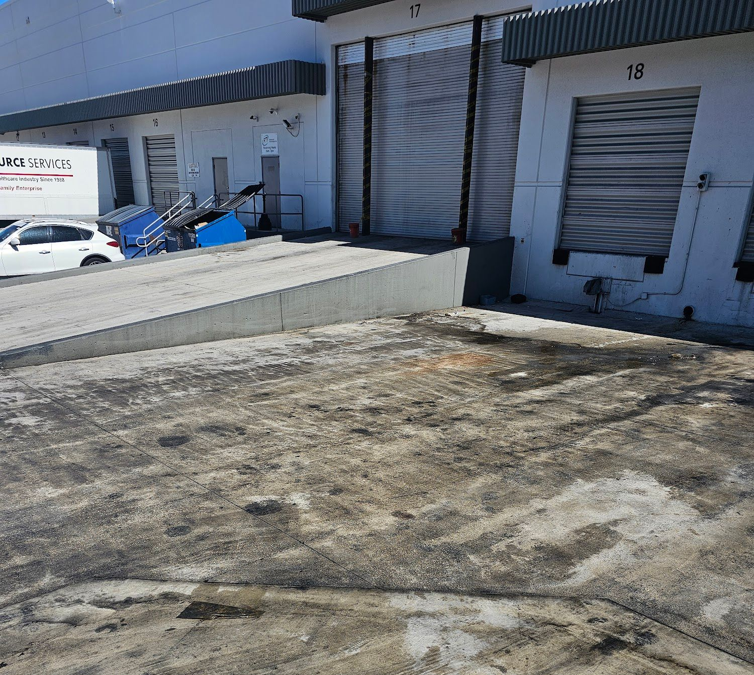 Concrete loading dock with a ramp, warehouse, and truck.