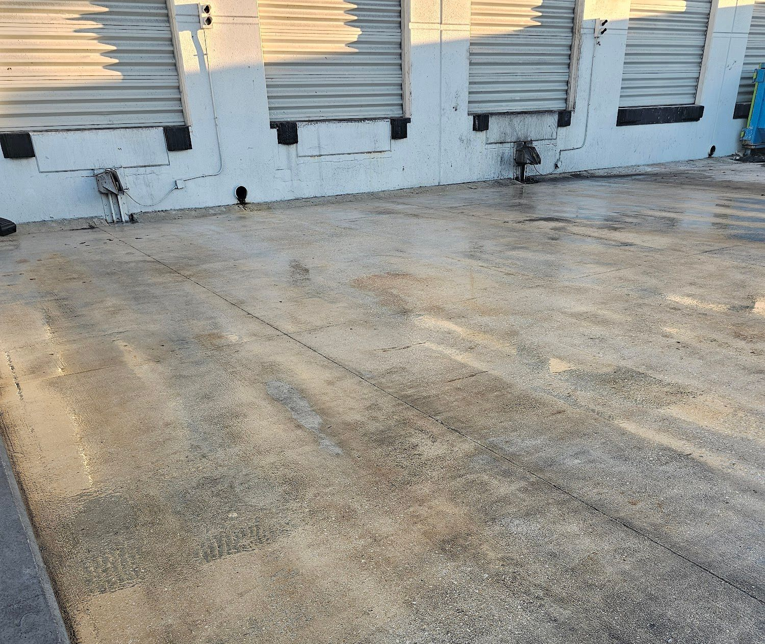 Concrete loading dock with several overhead garage doors.