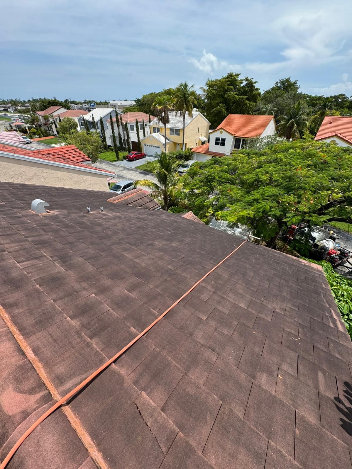 View of rooftops and houses on a sunny day, red-brown shingles in focus.