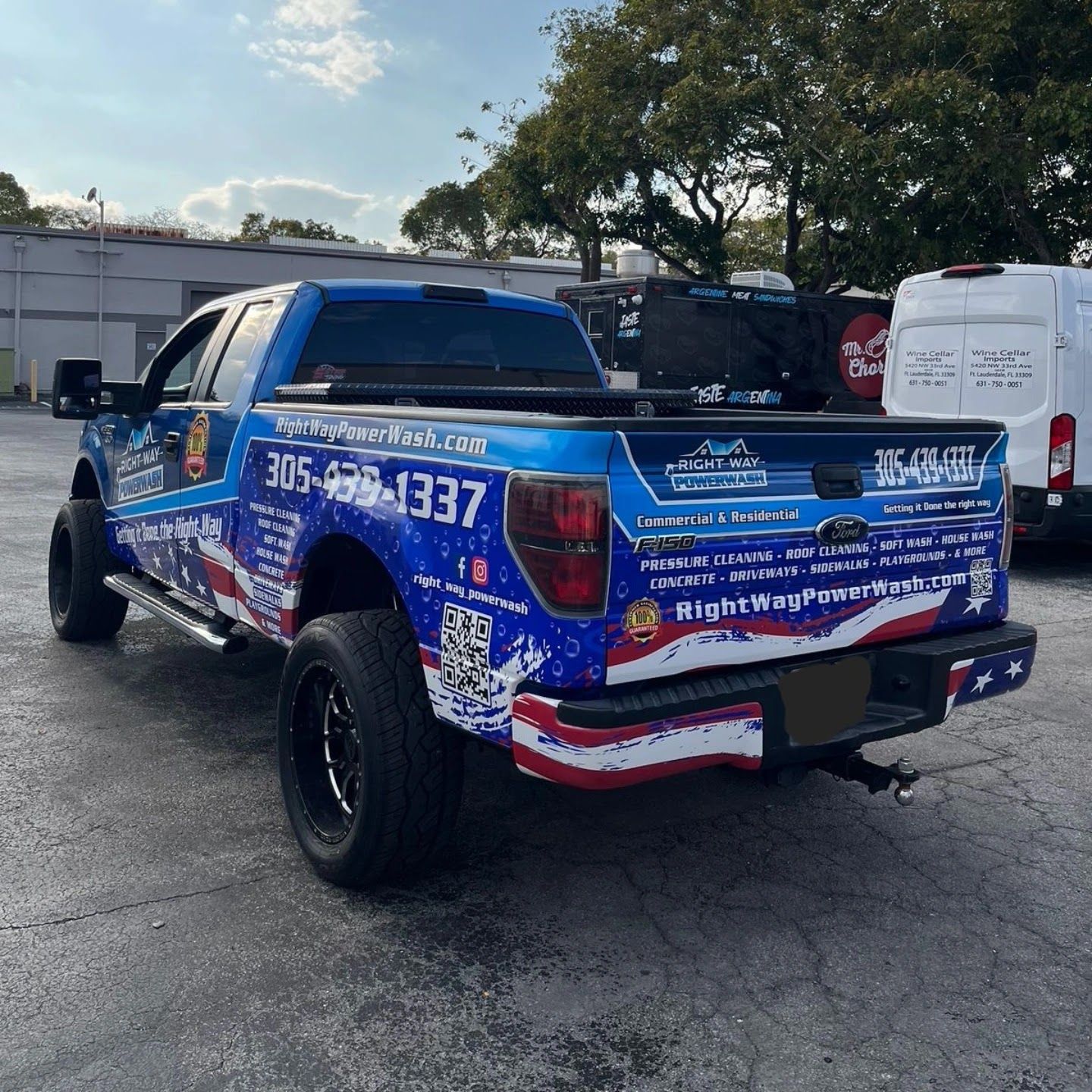 A blue Ford pickup truck with American flag wrap, parked outdoors.
