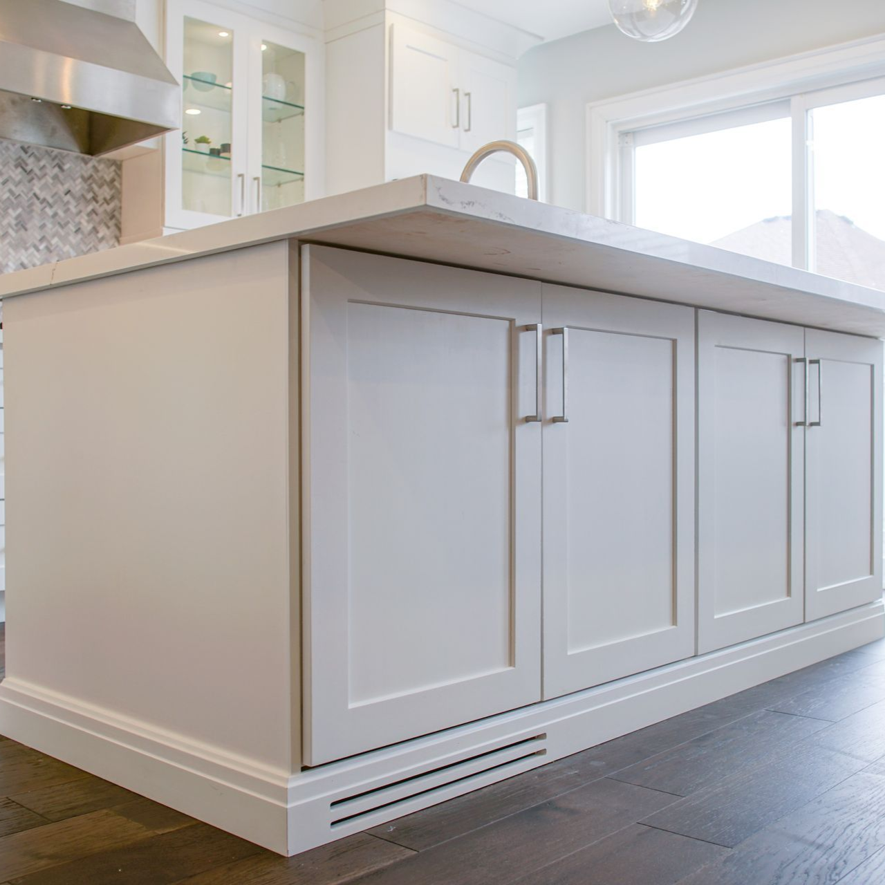 White kitchen island with cabinets, countertop, and hardware; wood flooring.