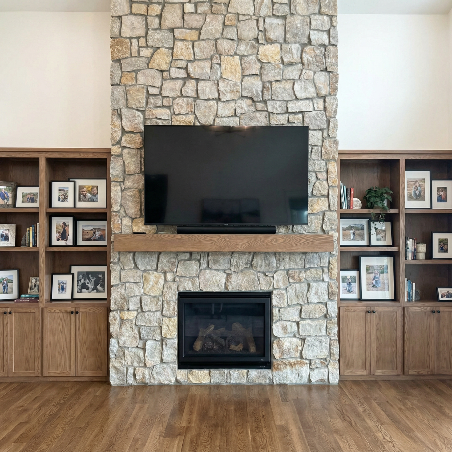 A living room with a stone fireplace and a flat screen tv.