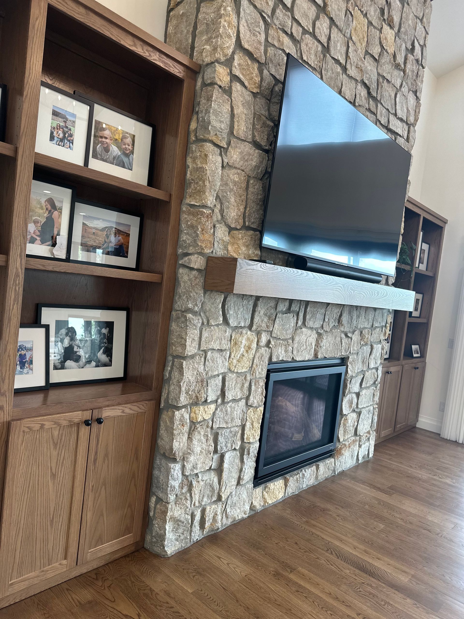 A living room with a stone fireplace and a flat screen tv.