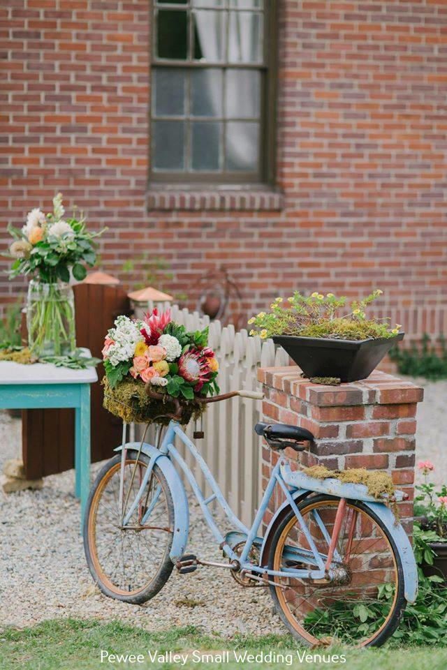 Pastel bicycle with flowers beside a turquoise table in a brick courtyard