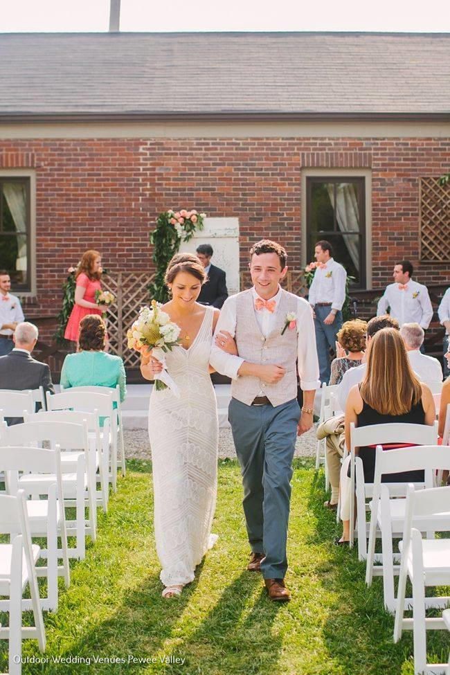 Bride and groom walking down a grassy aisle at an outdoor wedding ceremony