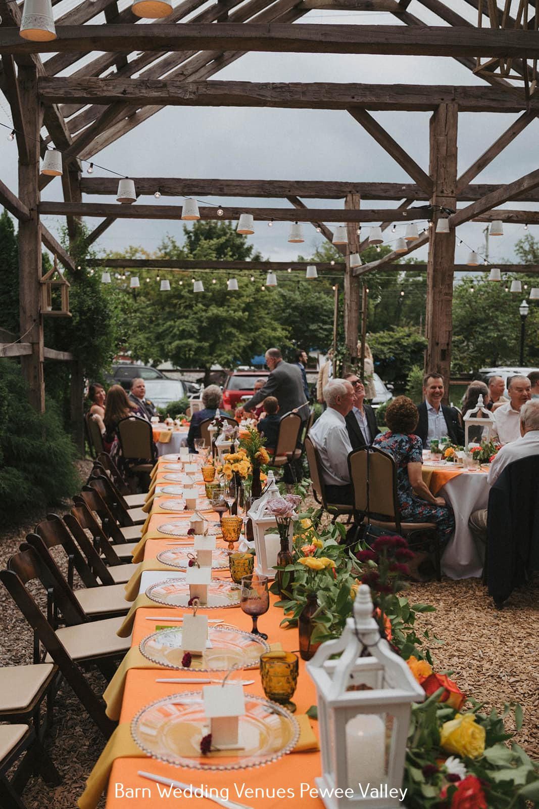 Outdoor reception under wooden pergola with long decorated dining tables and guests mingling
