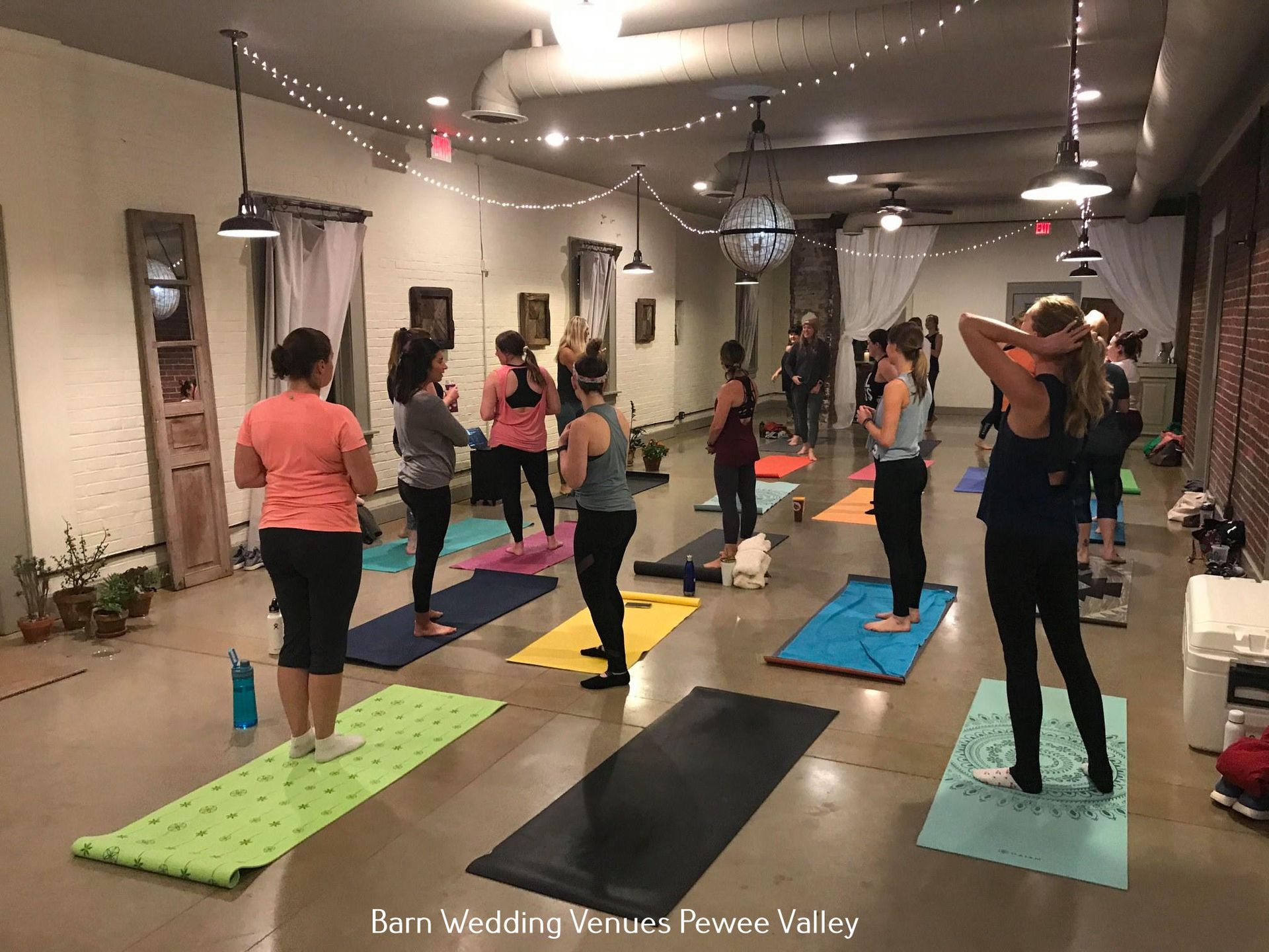 Yoga class with mats spaced in a bright studio, participants stretching near the mirrors.