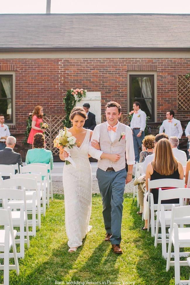 Bride and groom walking down an outdoor aisle at a wedding ceremony under bright sunlight