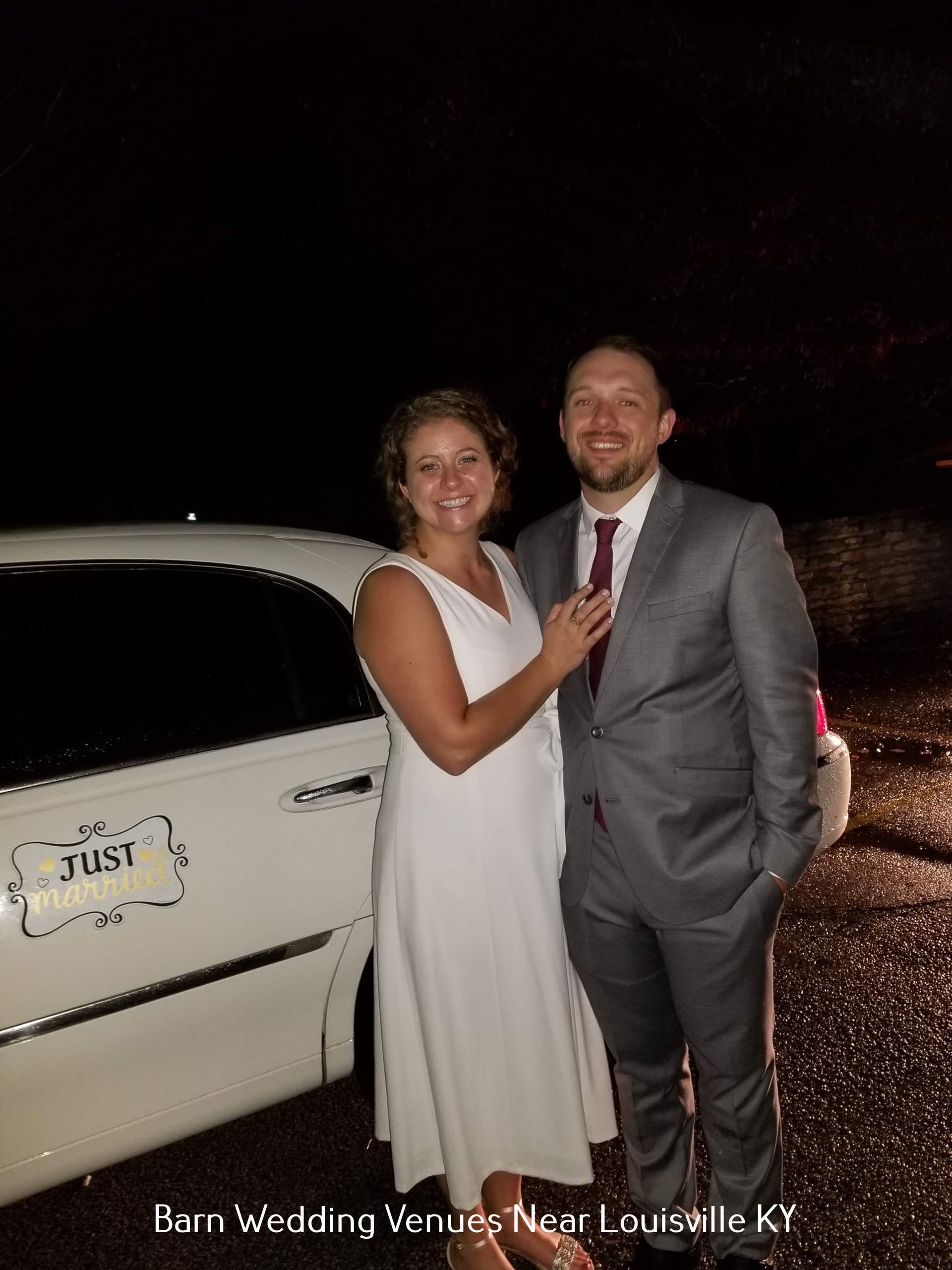 Couple posing beside a white limousine at night, with a wedding venue sign in the background