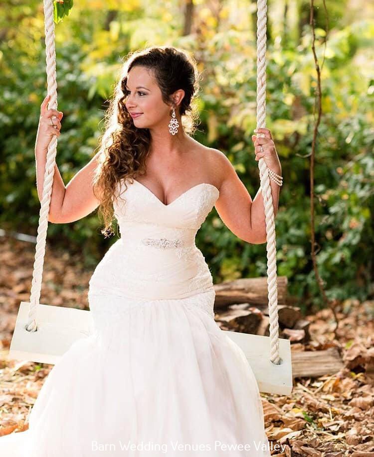Woman in a white strapless dress sitting on a swing in a leafy outdoor setting