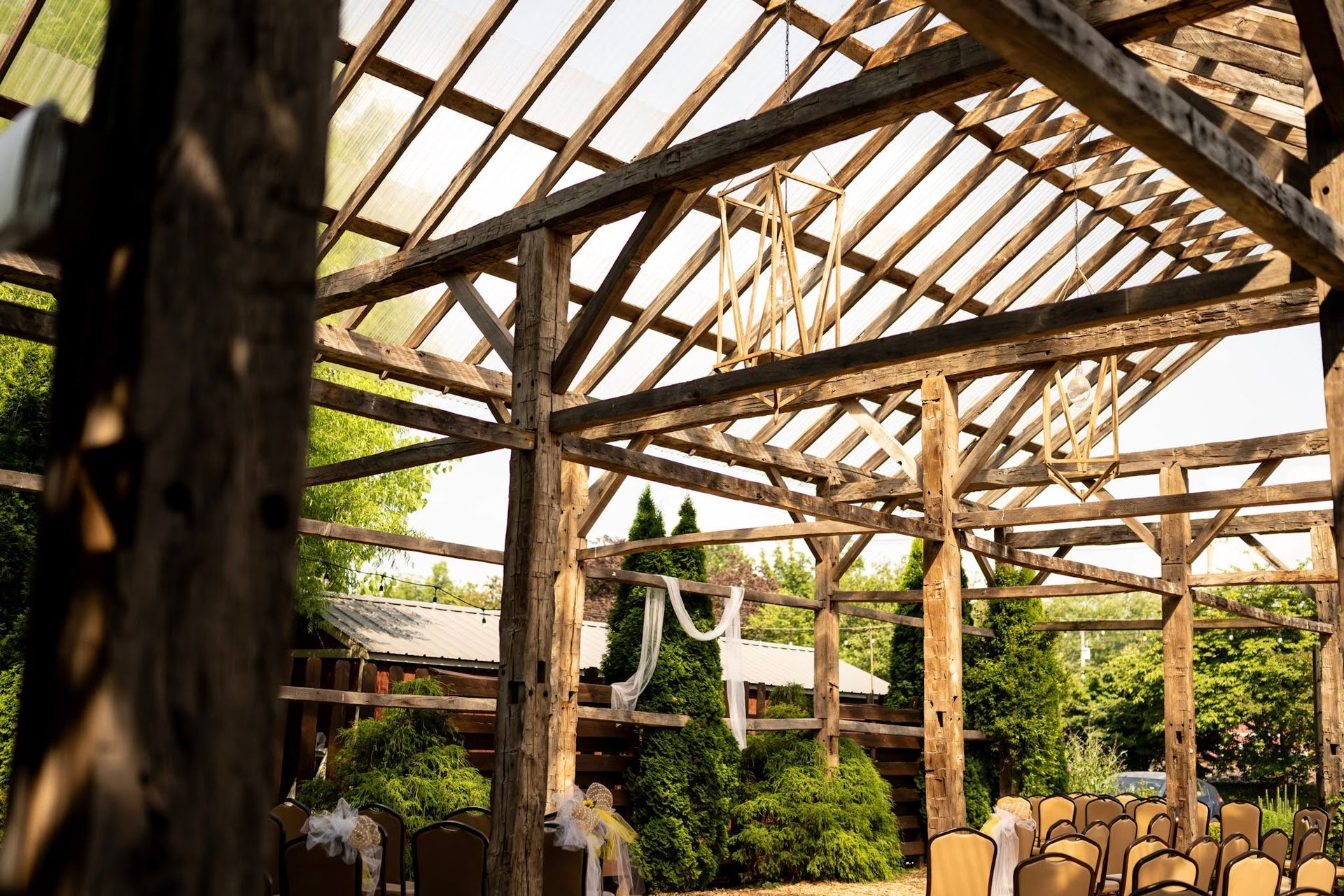 Wooden pergola frame in a garden patio with chairs and hanging laundry, lit by sunlight