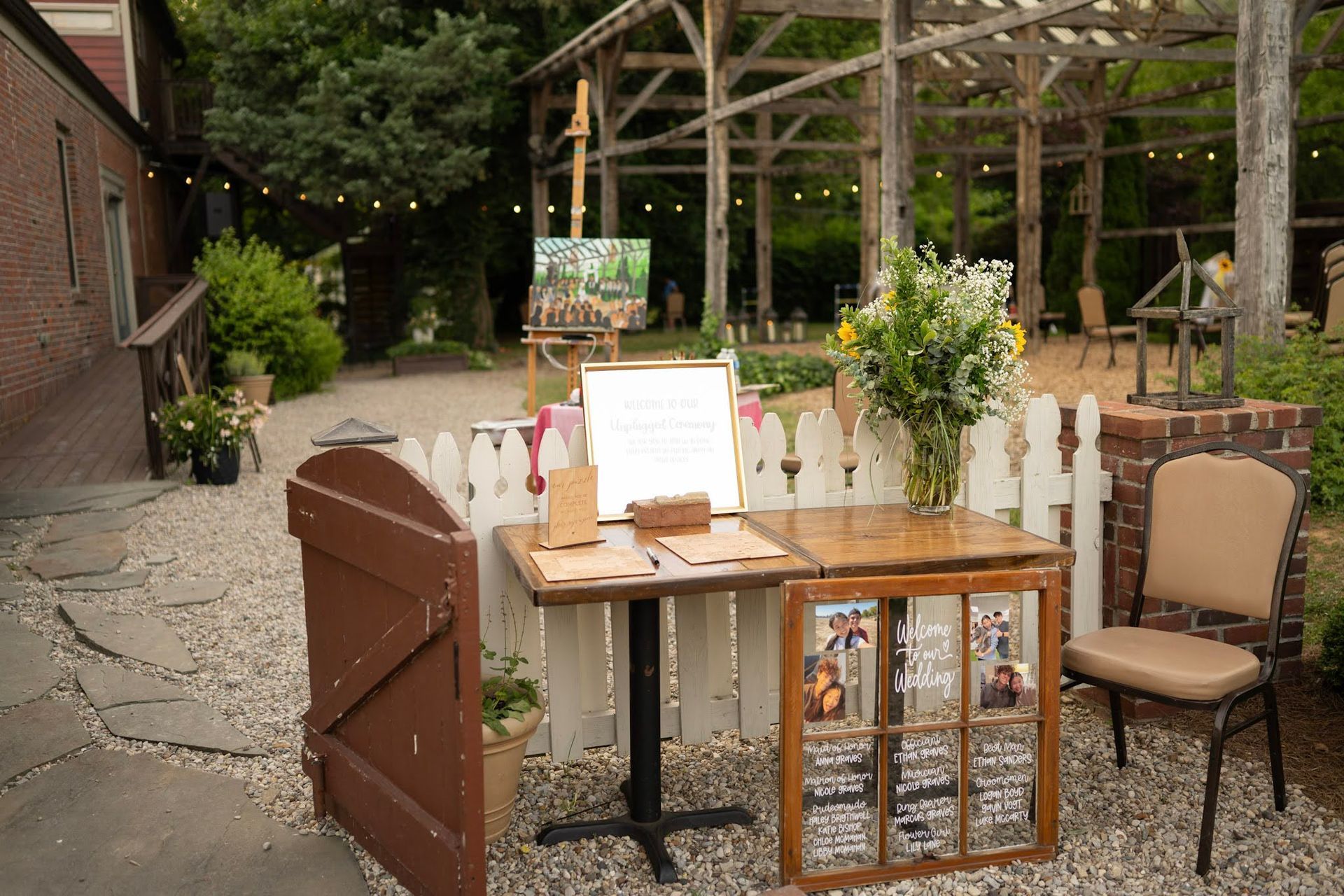 Outdoor café table with menu, drinks, and chairs under a wooden pergola in a garden courtyard