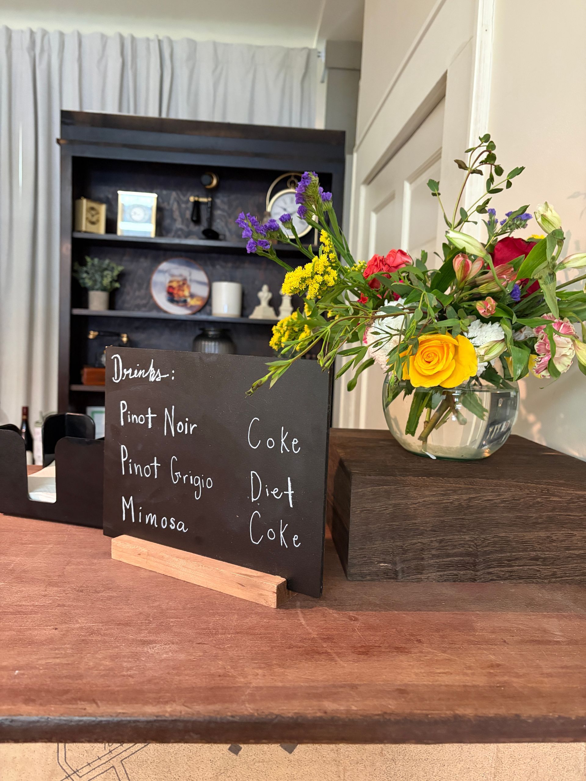 Drink menu chalkboard sign beside a floral arrangement