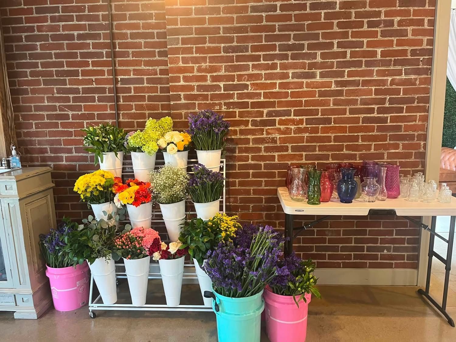Florist's table staged with buckets of fresh flowers against the brick wall
