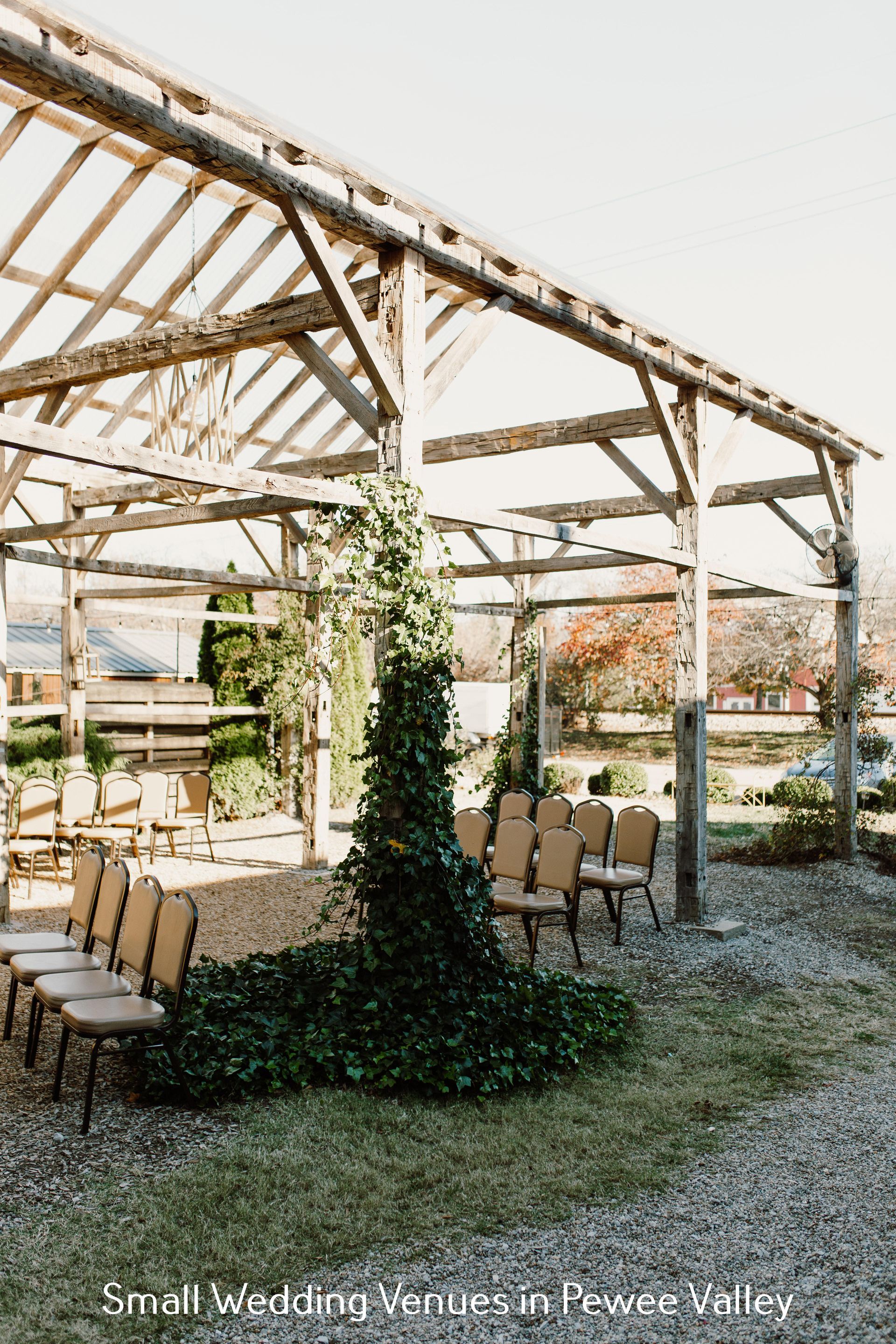 Outdoor wedding venue with wooden pergola, white chairs, and green vines in a rustic garden setting