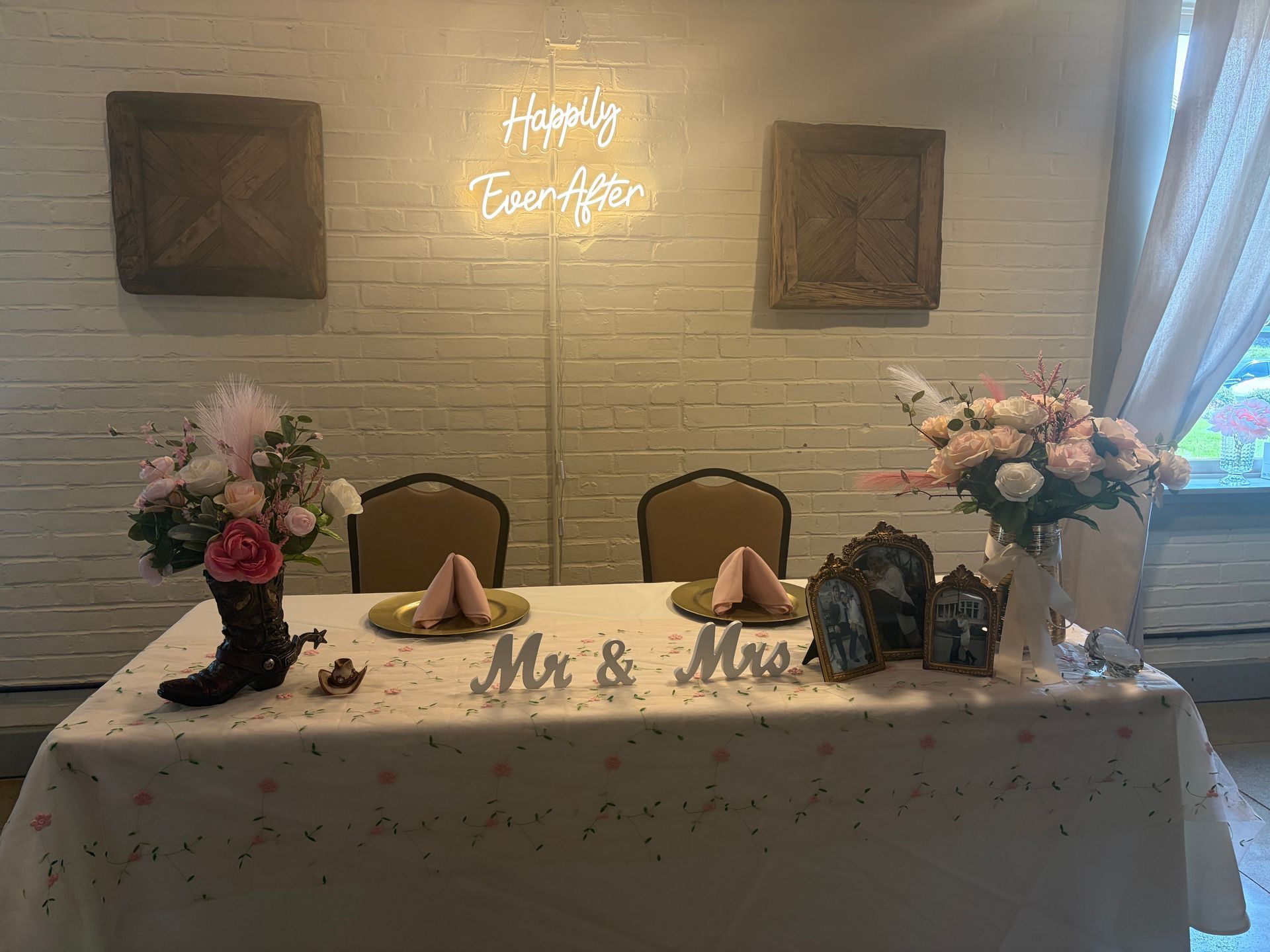 Sweetheart table set with a Mr. and Mrs. sign and cowboy boot decor, no one seated