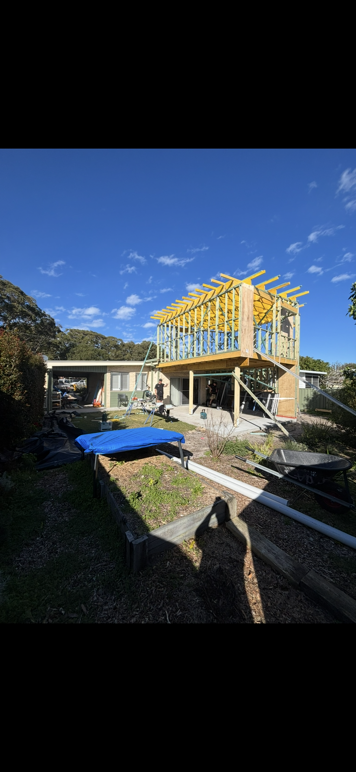 A White Carport Covers a Wooden Deck, With a House in the Background. the Sky is Blue With Some Clouds — Campbell Built in Nelson Bay, NSW
