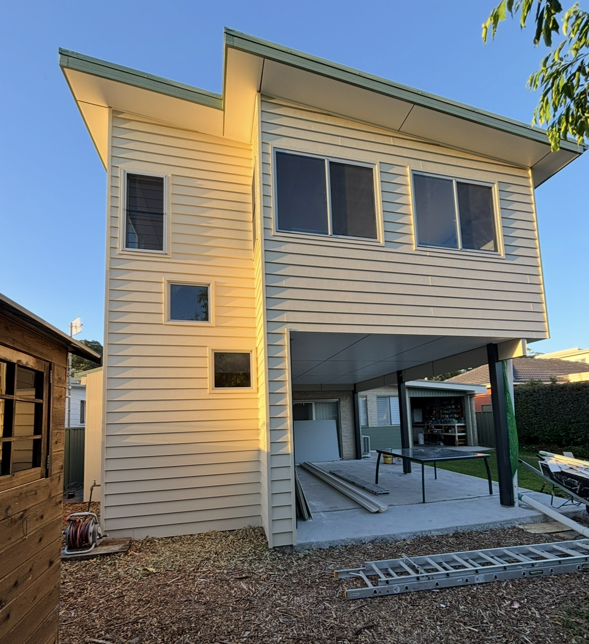 Modern white house with gray garage door and driveway; manicured front yard — Campbell Built in Anna Bay, NSW
