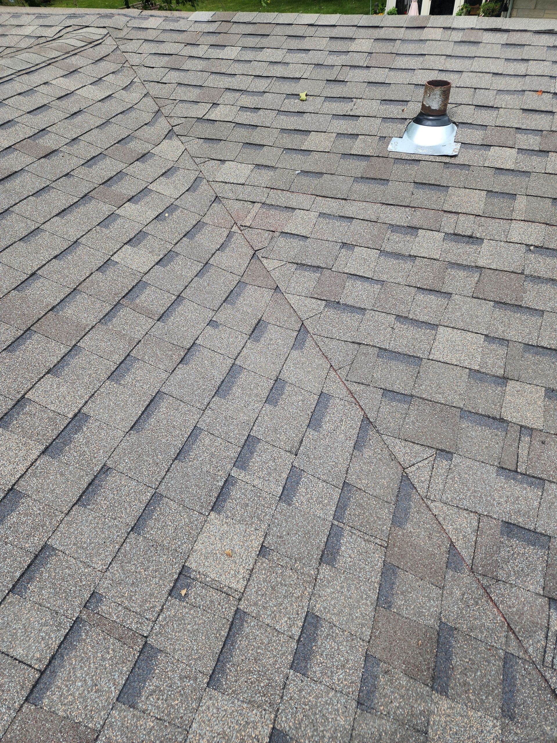 Gray asphalt shingle roof with a vent pipe and angled seams.