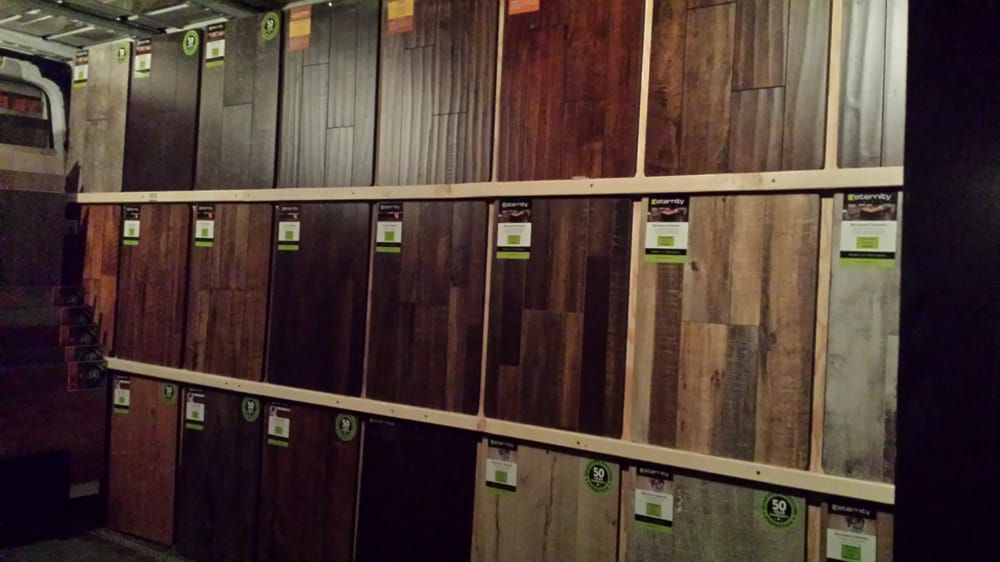 A store display wall featuring a wide selection of wood flooring samples in various shades, grains, and textures.