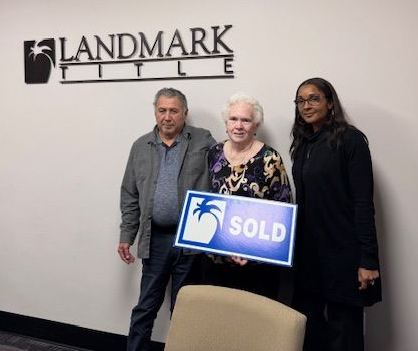 Three people in an office smiling, holding a