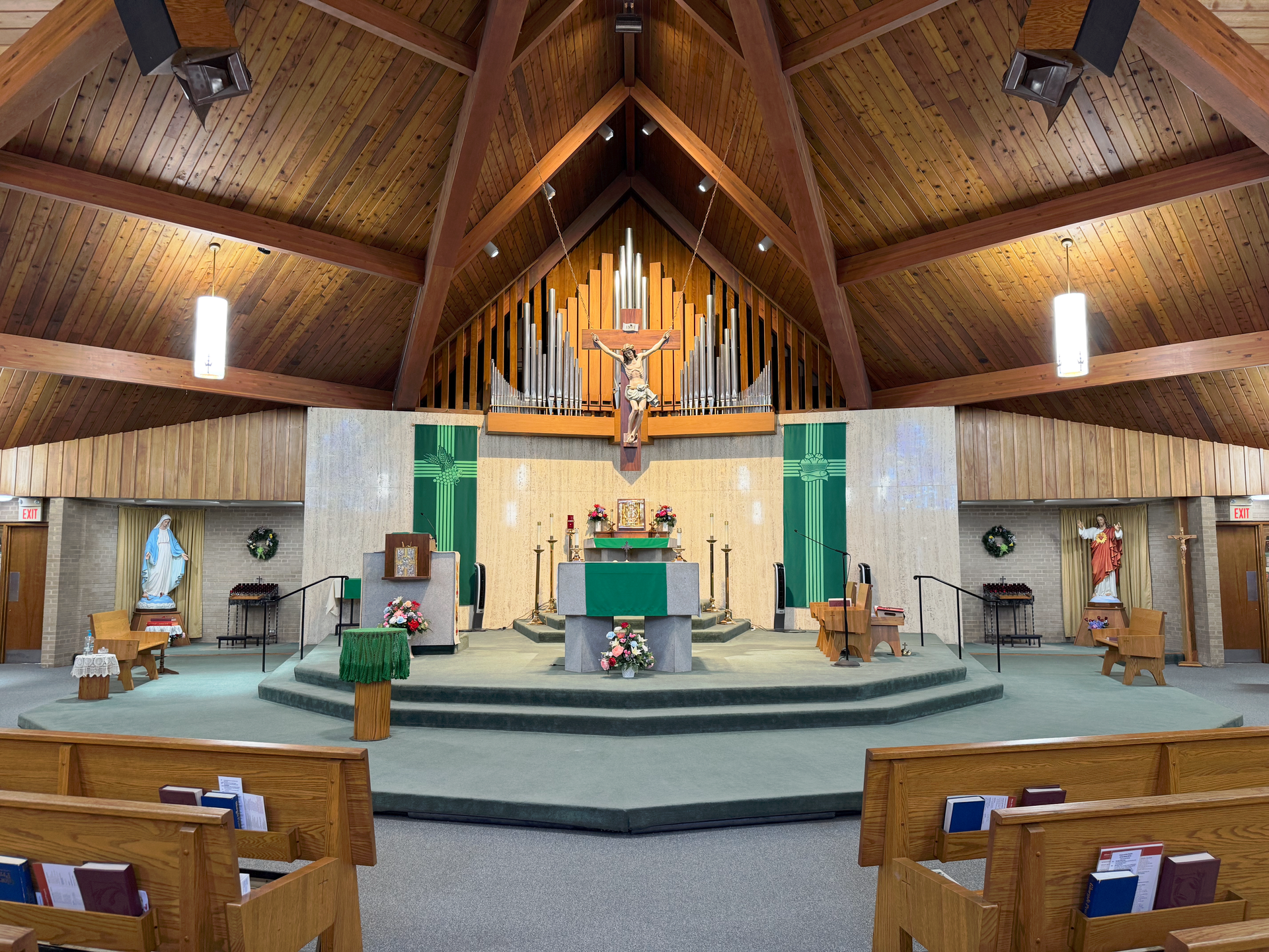 Interior of a church with wooden beams, altar, crucifix, and pews.