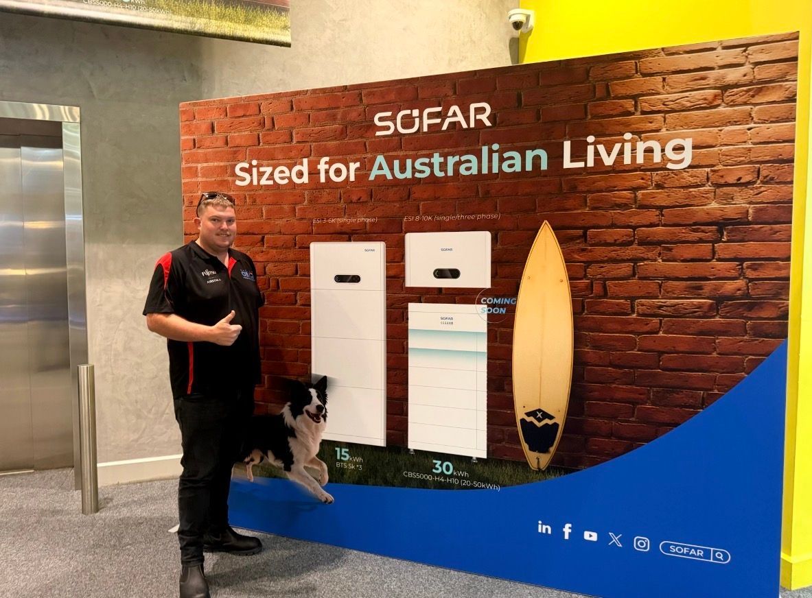 Man standing beside a dog in front of a SOFAR display with surfboards — Macleay Energy Solutions In Crescent Head, NSW