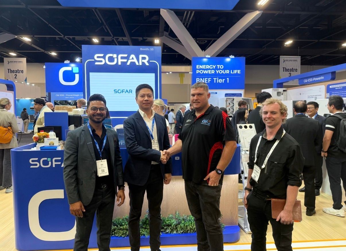 People posing at a SCFAR booth in a busy trade show hall, with blue signage and displays — Macleay Energy Solutions In Crescent Head, NSW