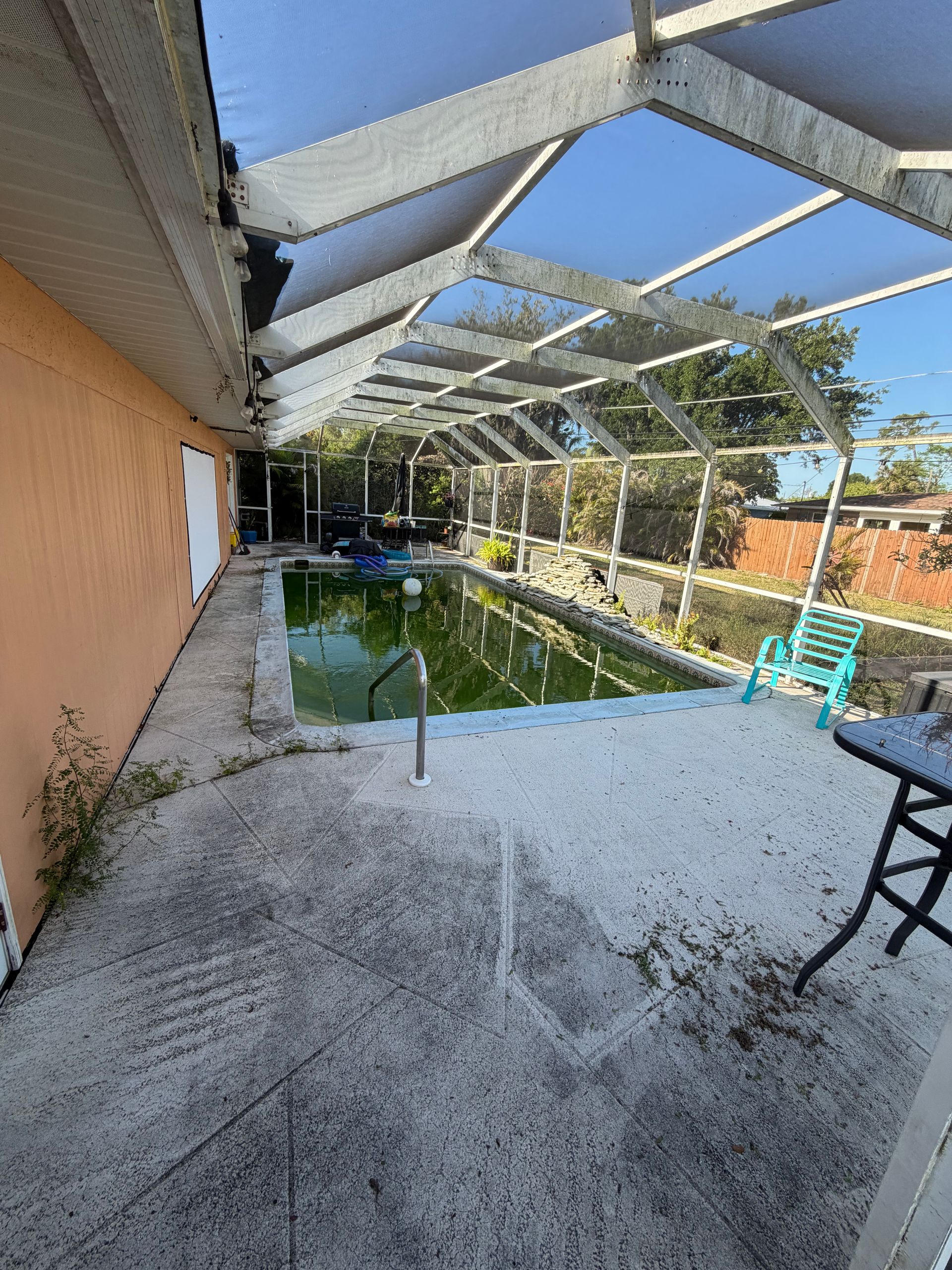 Covered backyard patio with a screened pool and blue sky visible through the roof panels