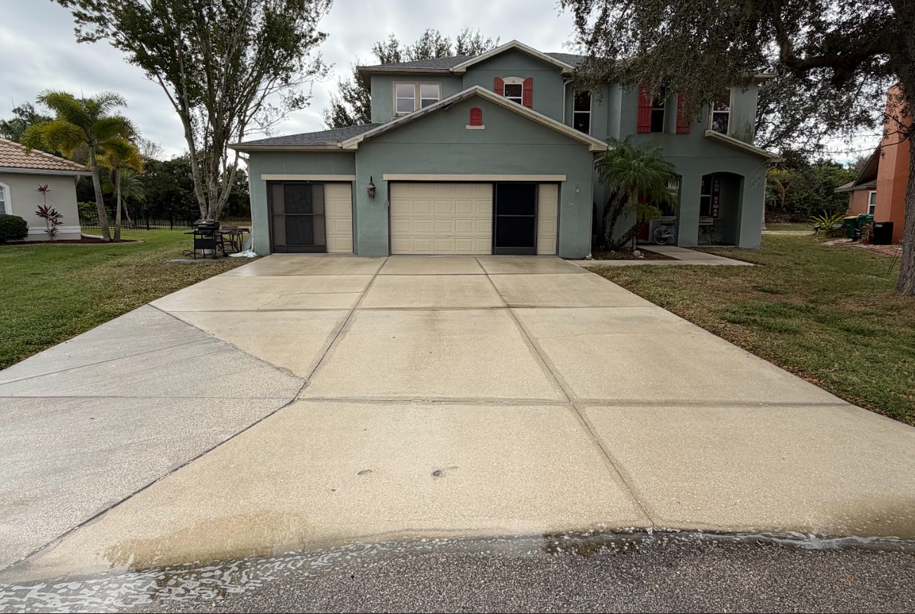 Suburban house with a wide concrete driveway and two-car garage under cloudy skies