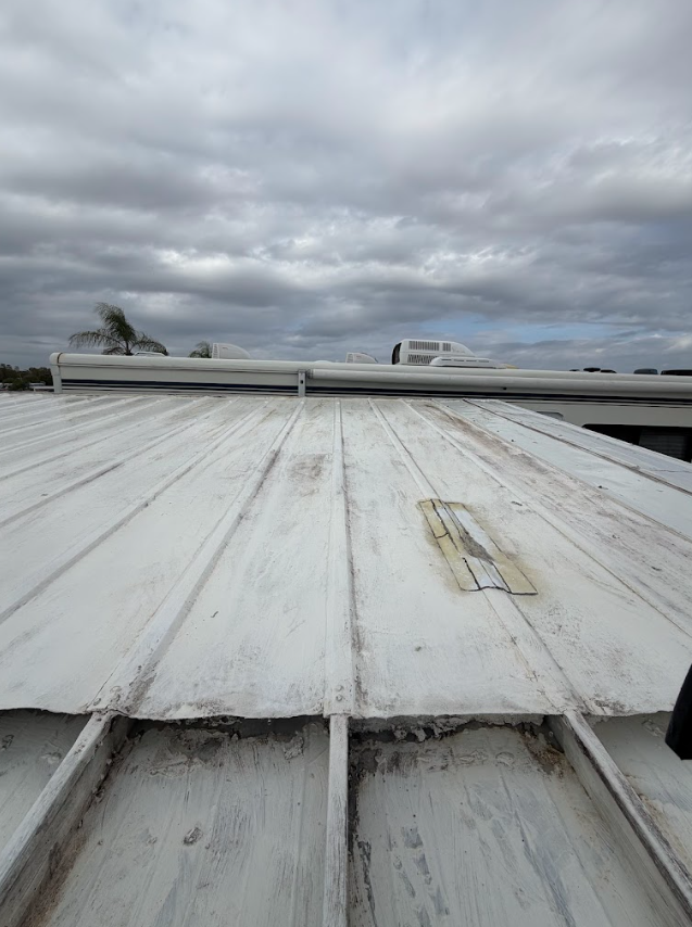 Cloudy sky over a white metal rooftop with seams and vents visible