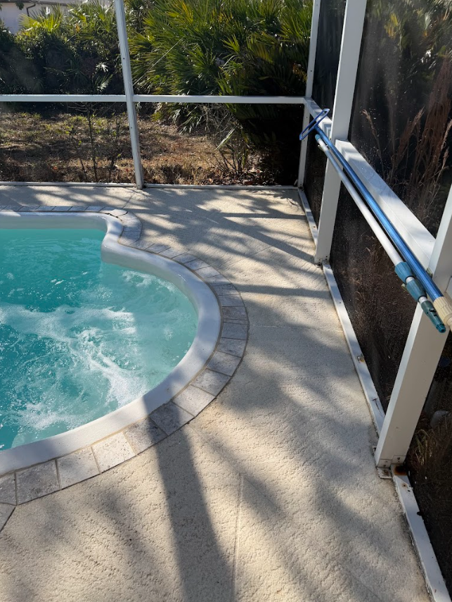 Backyard pool corner with turquoise water, concrete deck, and screened patio railing