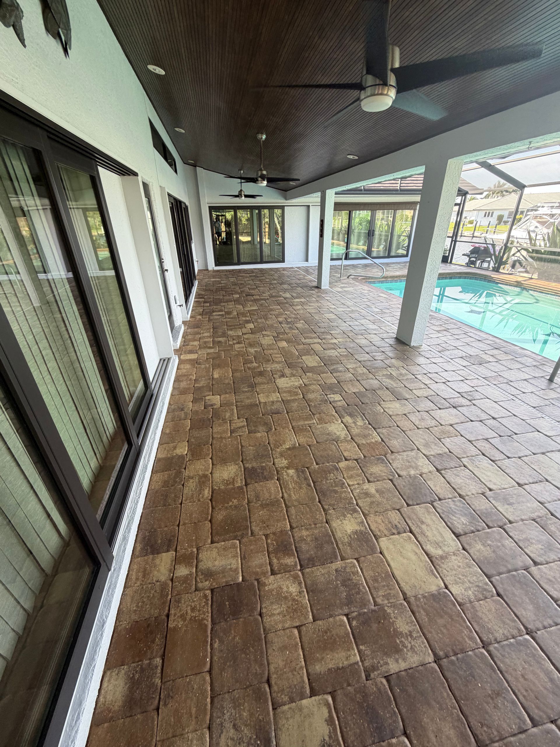Screened patio with concrete floor, white railing, and a small blue hot tub beside a metal handrail