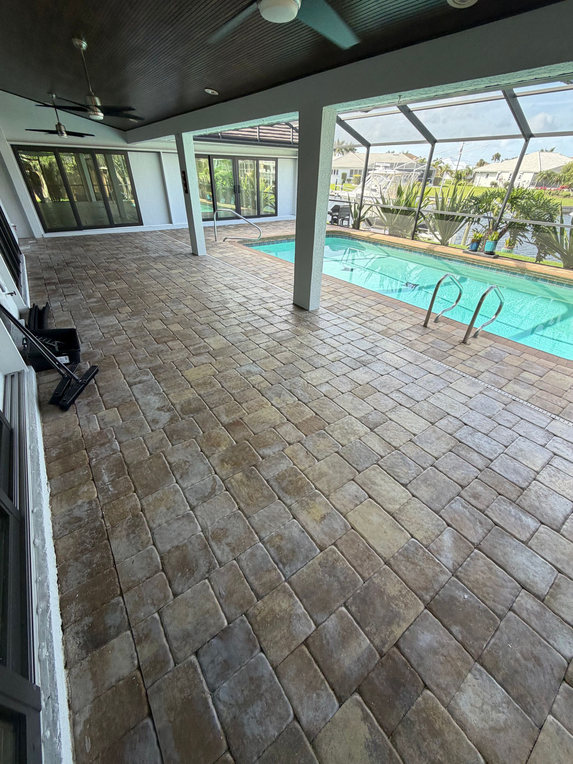 Screened patio beside a swimming pool with a hose on the concrete floor
