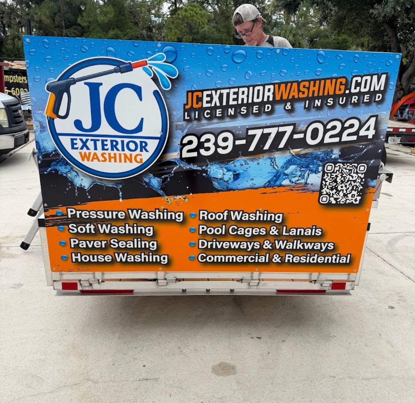 JC Exterior Washing trailer sign with blue and orange branding, services list, phone number, and QR code