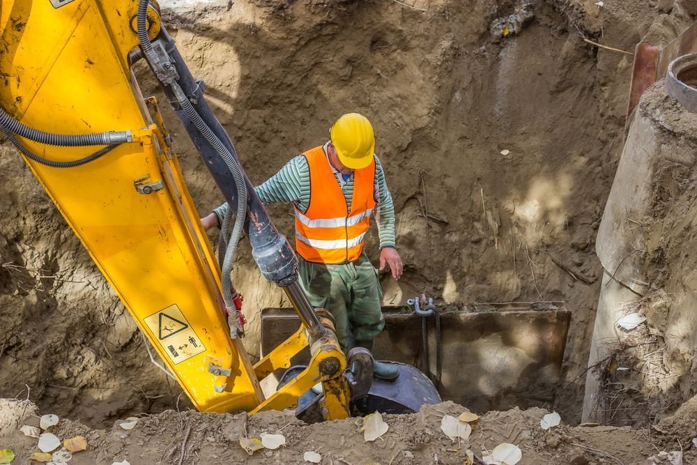 A Construction Worker is Digging a Hole With a Yellow Excavator — Tomac Civil In Burleigh Heads, QLD