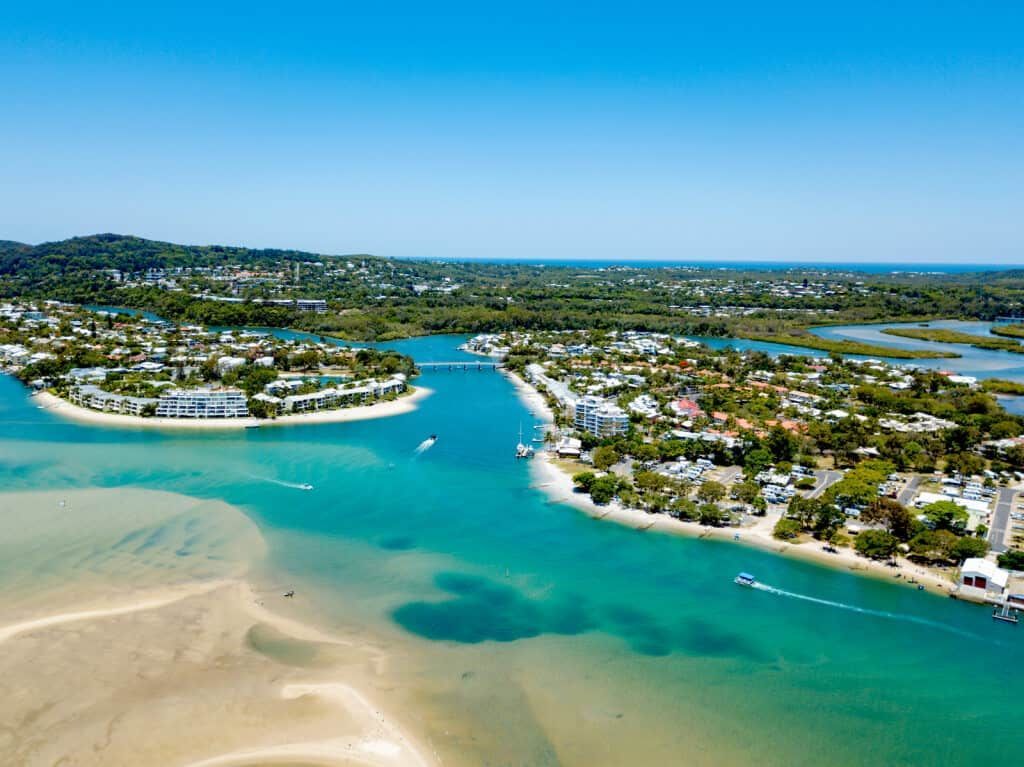 Aerial View of A Turquoise Waterway with Islands, Houses, Boats, and A Sandy Beach Under a Clear Blue Sky — Tomac Civil In Sunshine Coast, QLD
