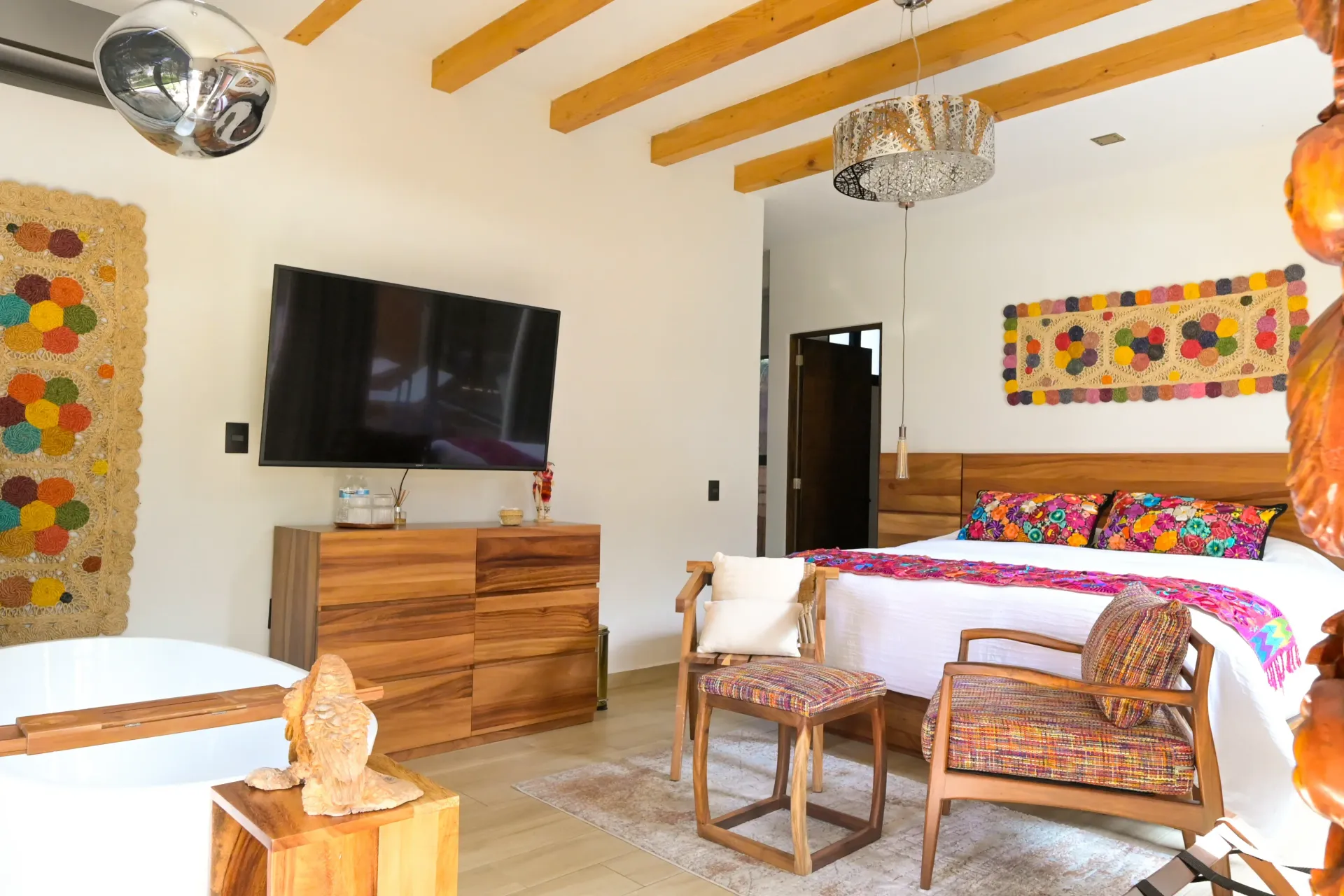 Un dormitorio con una cama, sillas, cómoda y televisión.