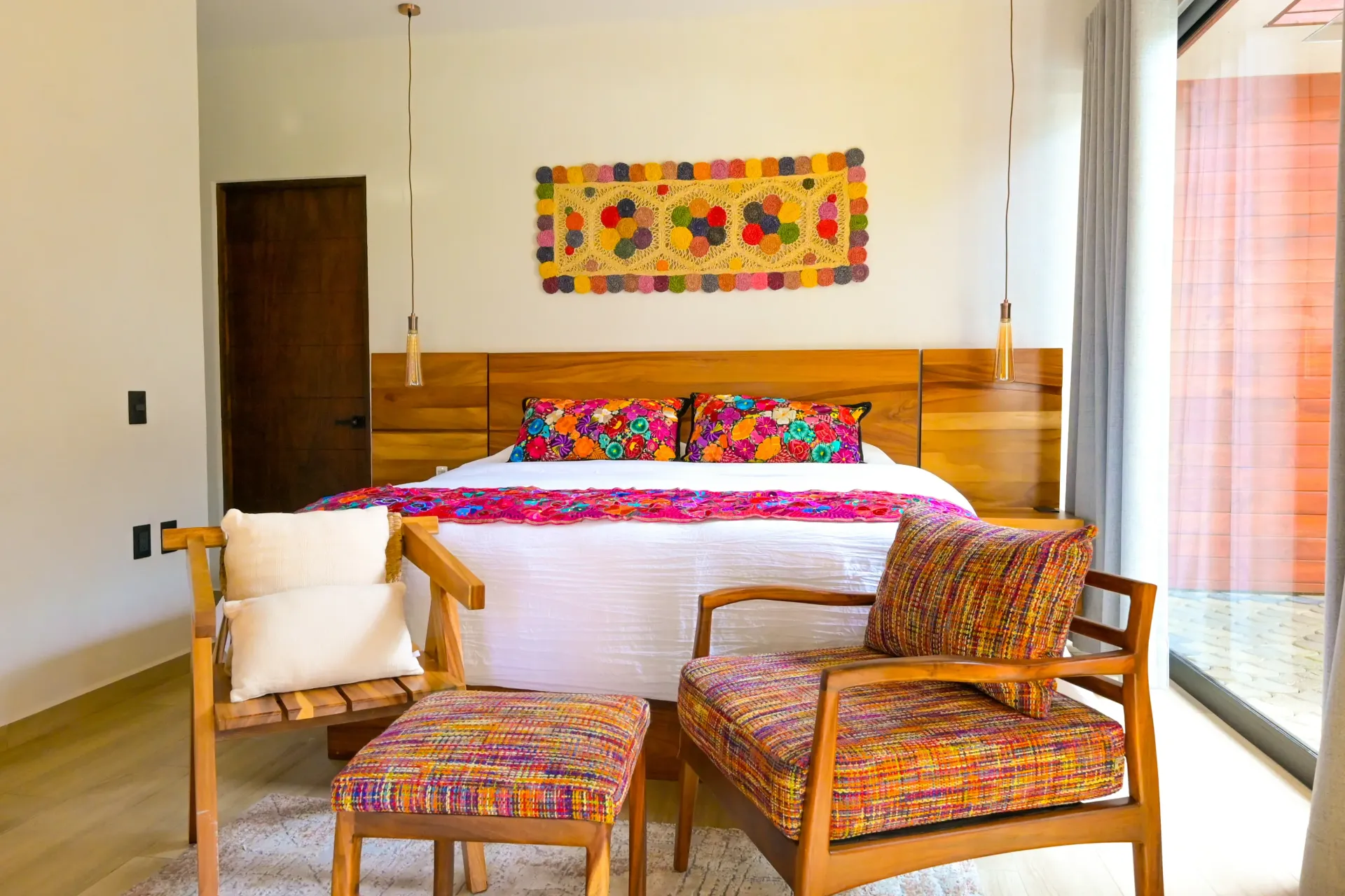 Un dormitorio con una cama grande, sillas, otomana y un cuadro en la pared.