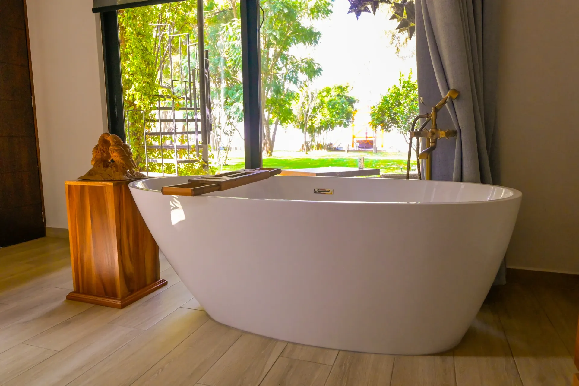 Una bañera está colocada en un baño al lado de una ventana.