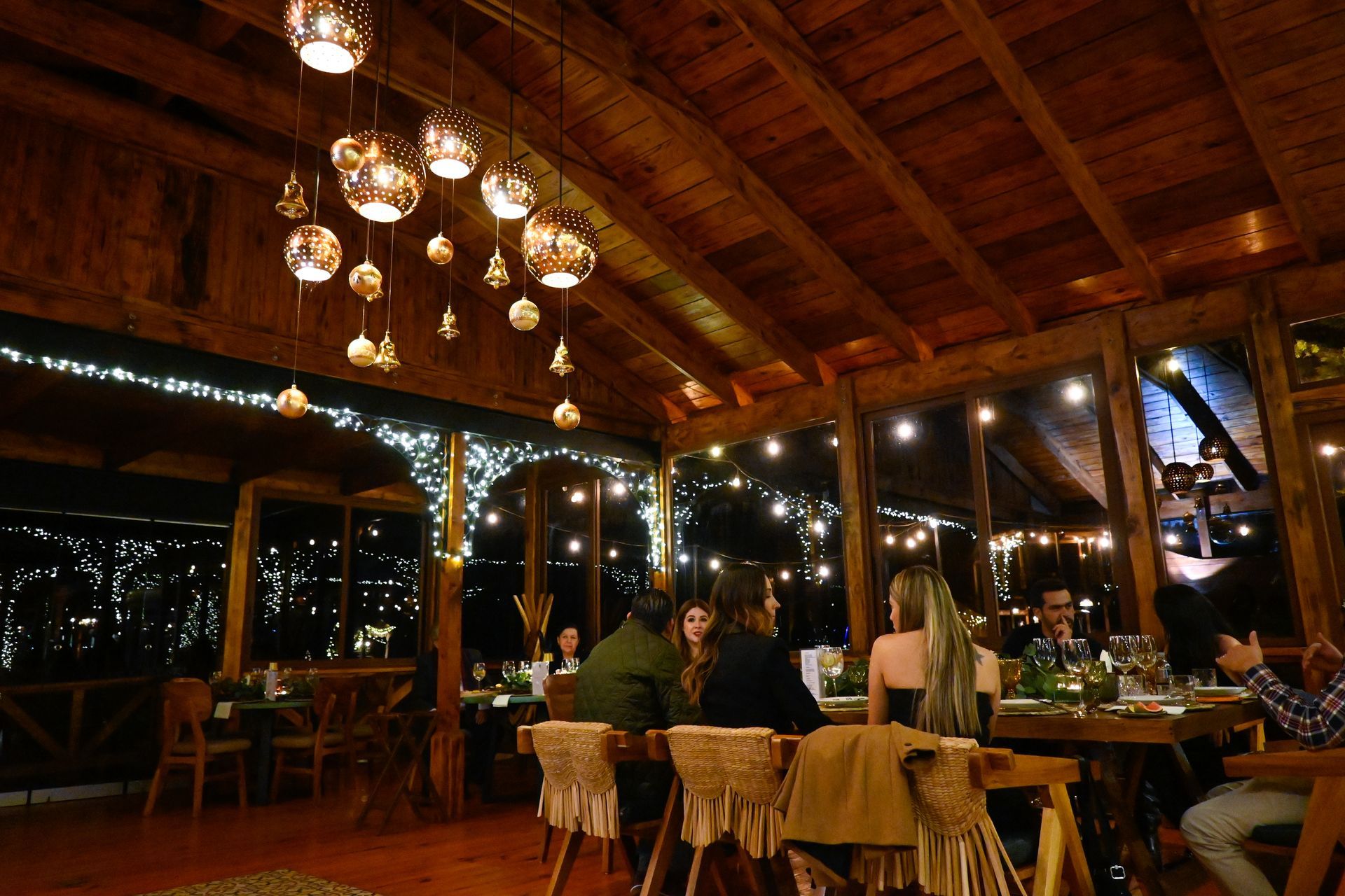 Un grupo de personas están sentadas en mesas en un restaurante por la noche.