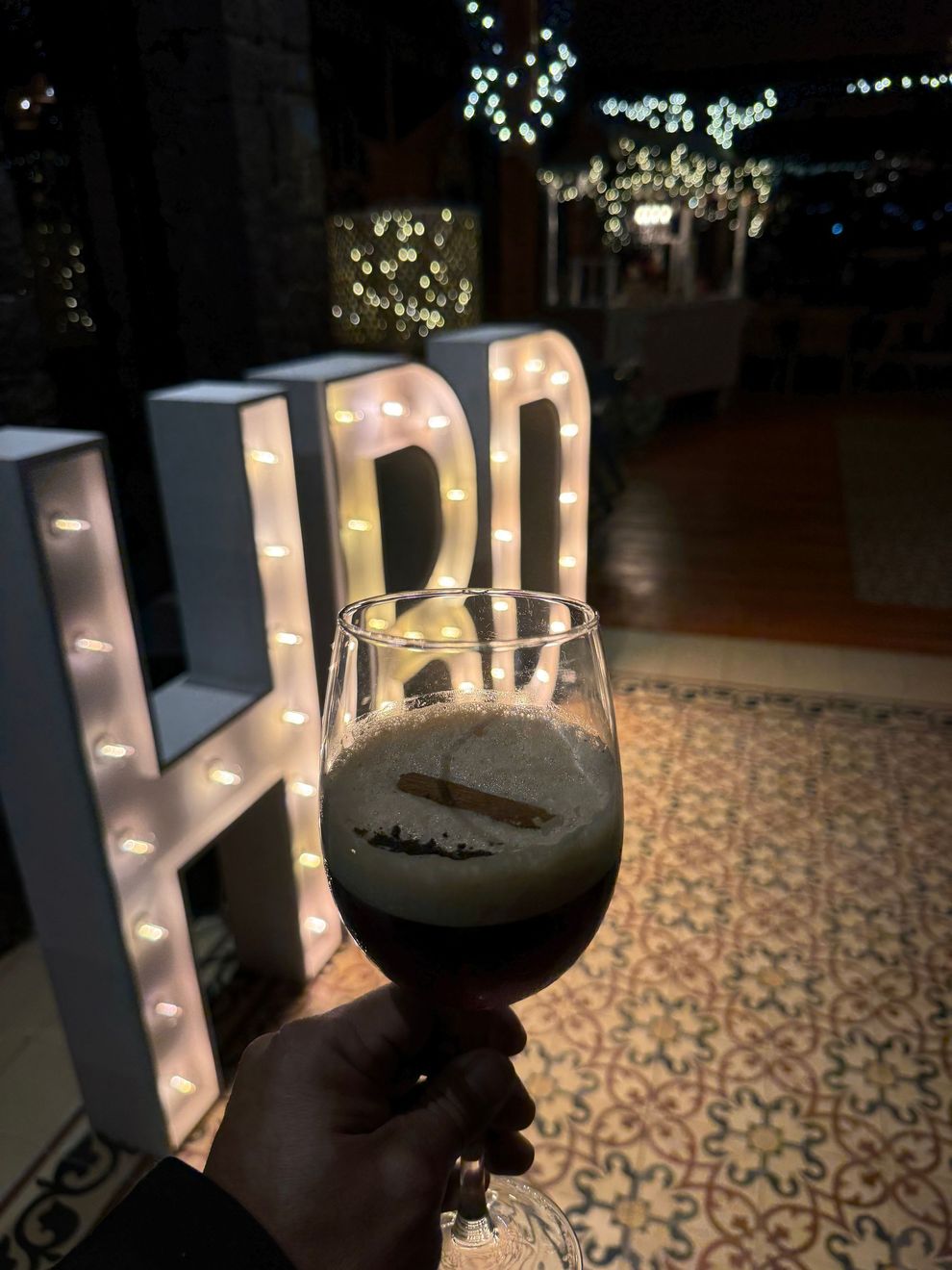 Una persona sostiene un vaso de cerveza con la letra h en el fondo.