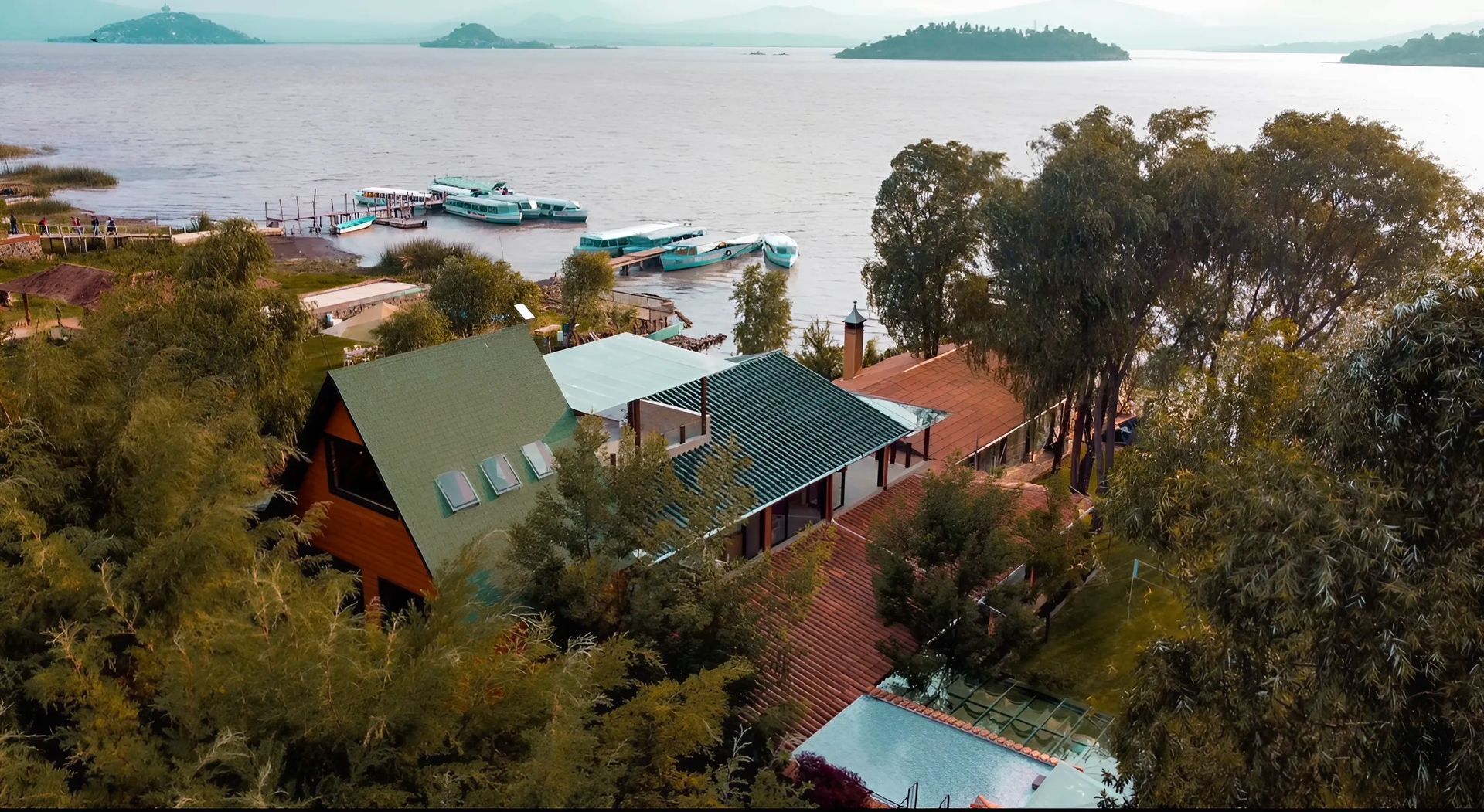 An aerial view of a house surrounded by trees next to a body of water.
