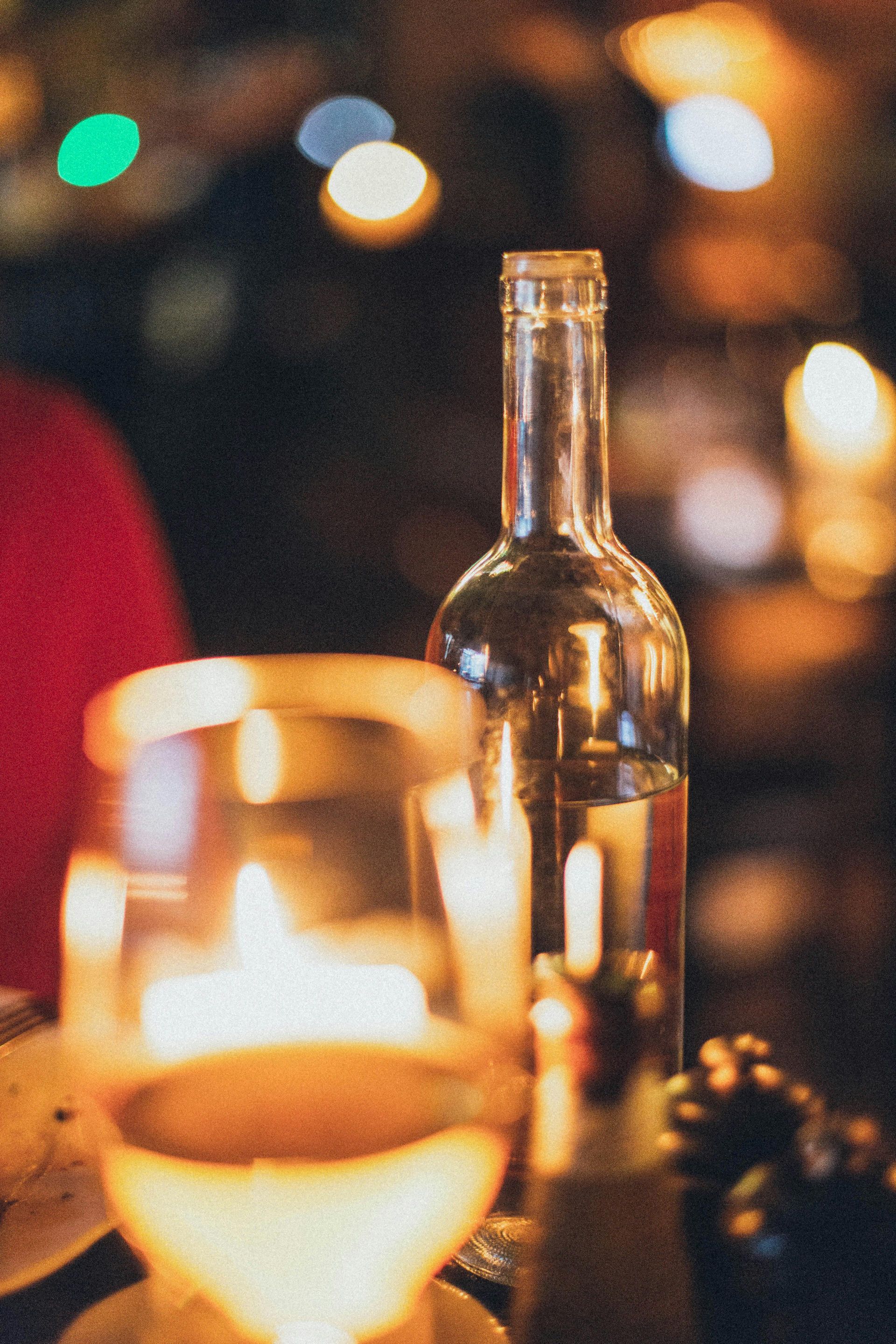 Una botella de vino y una copa de vino están sobre una mesa.