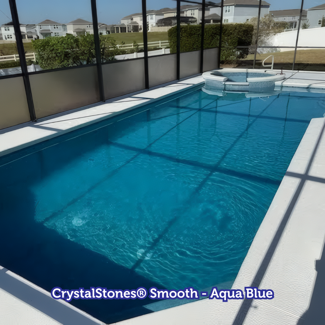 Swimming pool with blue water and white deck. The pool is surrounded by a screen enclosure.