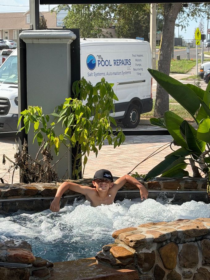 Person swimming in a stone water feature, with a delivery truck and leafy plants in the background