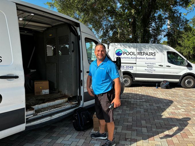 Man standing beside an open white work van in a driveway, with a pool repairs van in the background